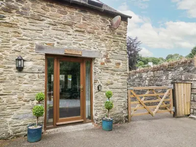 a stone house with two potted plants in front of it at Miller's Lodge in Liskeard