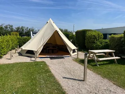 a tent with a picnic table and a bench at The Laurels Holiday Park & Cottages nr Padstow and Wadebridge in Wadebridge