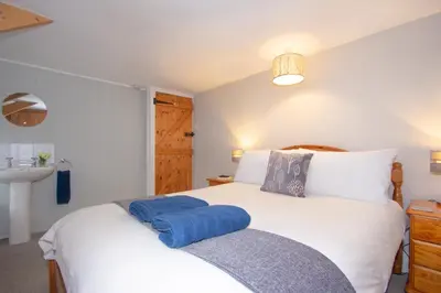 a bedroom with a white bed with a blue towel on it at The Laurels Holiday Park & Cottages nr Padstow and Wadebridge in Wadebridge