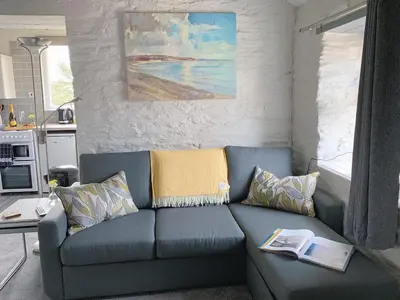 a living room with a blue couch with books on it at The Laurels Holiday Park & Cottages nr Padstow and Wadebridge in Wadebridge