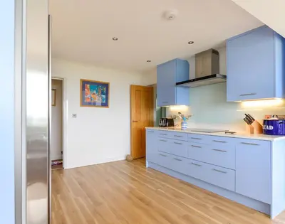 a kitchen with blue cabinets and a wooden floor at Sea Mist in Polzeath
