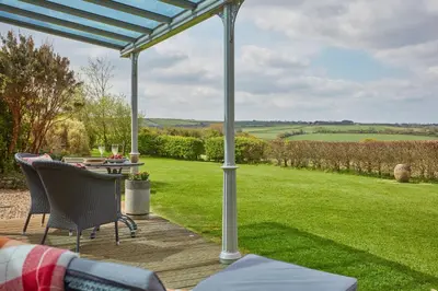 a patio with a table and chairs and a view of a field at Meadow View in Newquay