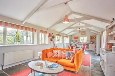 a living room with an orange couch and a table at Meadow View in Newquay