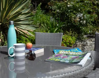 a table with a bottle of water and books on it at Brookside in Polzeath