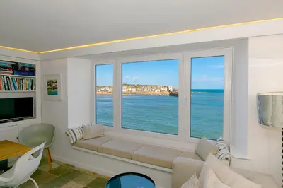 a living room with a large window overlooking the ocean at Men an Mor in St Ives