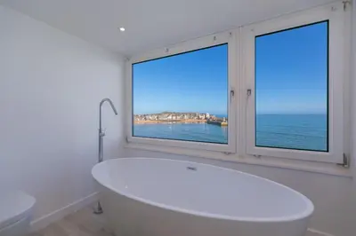 a white bath tub in a bathroom with two windows at Men an Mor in St Ives
