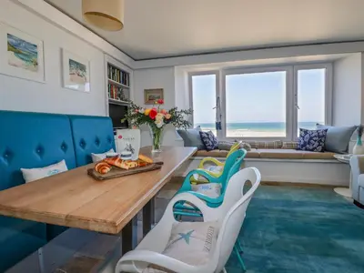 a living room with a table and chairs and the ocean at Men an Mor in St Ives