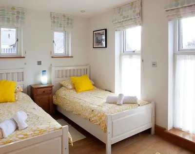 a bedroom with two beds and two windows at Ossco in Polzeath