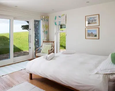a bedroom with a large white bed and a window at Ossco in Polzeath