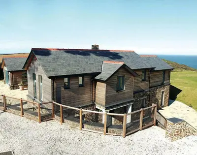 a large wooden house on top of a beach at Ossco in Polzeath