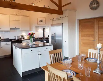 a kitchen with a wooden table with chairs and a dining room at Ossco in Polzeath