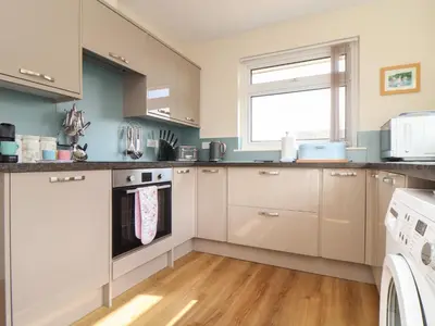 a kitchen with white cabinets and a window at Tremethic in St Austell