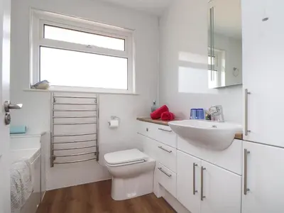 a bathroom with a toilet and a sink and a window at Tremethic in St Austell