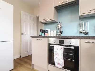 a kitchen with white cabinets and a black oven at Tremethic in St Austell