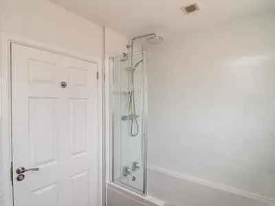 a bathroom with a shower and a white door at Tremethic in St Austell