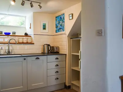 a kitchen with white cabinets and a sink at Trevivian House in Boscastle
