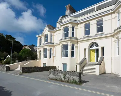 a white house with a yellow door on a street at 4 The Terrace in Padstow