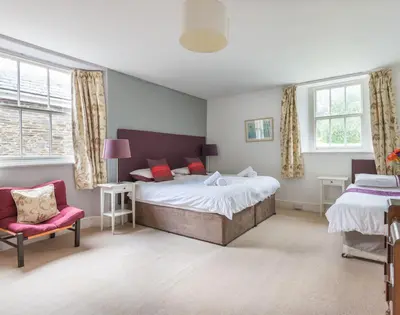 a bedroom with a bed and a chair and windows at 4 The Terrace in Padstow
