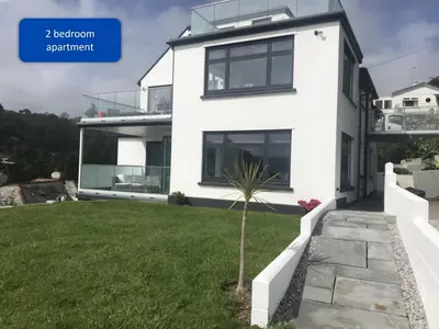 a white house with a green yard at Ocean View Apartments in Looe
