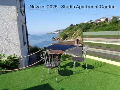 two chairs and a table on a balcony with the ocean at Ocean View Apartments in Looe
