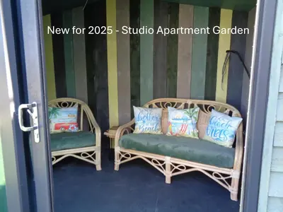 two wicker chairs with pillows sitting in a doorway at Ocean View Apartments in Looe