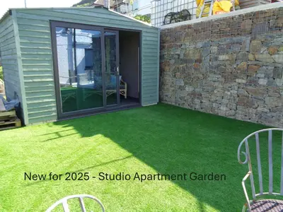 a garden room with a patio with green grass at Ocean View Apartments in Looe