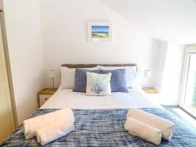 a bedroom with a large bed with two pillows at Kelmscot in Port Isaac