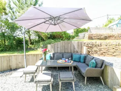a patio with a table and an umbrella at Kelmscot in Port Isaac
