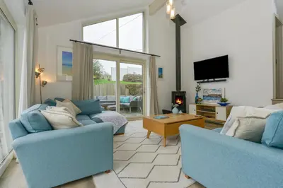 a living room with two blue chairs and a tv at Kelmscot in Port Isaac