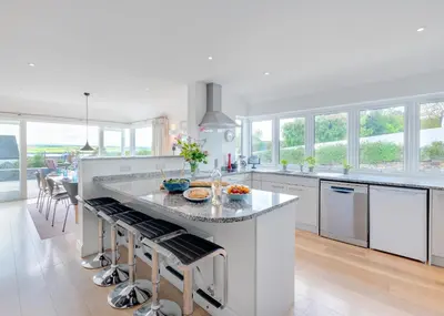 a white kitchen with a large island in the middle at Landers Field in Padstow