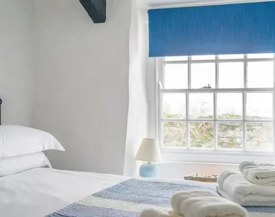 a white bedroom with a bed and a window at Cloam Cottage in Port Isaac