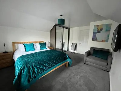 a bedroom with a bed and a chair in it at Camellia Cottage in Camborne