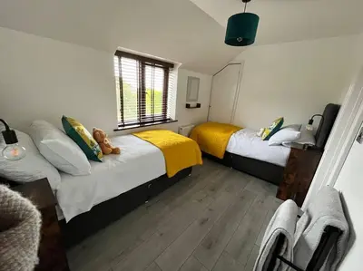 a bedroom with two beds and a window at Camellia Cottage in Camborne