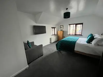 a bedroom with a bed and a couch and a tv at Camellia Cottage in Camborne