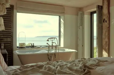 a bedroom with a tub and a view of the ocean at The Tidal Shore - Adults Only - in Marazion