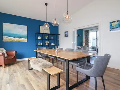 a dining room with blue walls and a wooden table and chairs at Beach Haven in Perranporth