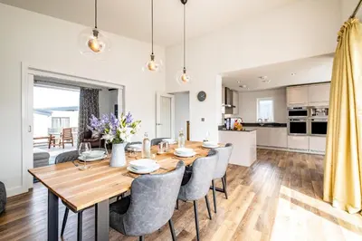 a dining room and kitchen with a wooden table and chairs at Beach Haven in Perranporth