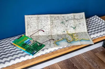 a book and a map on top of a bed at Beach Haven in Perranporth
