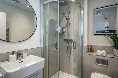 a bathroom with a shower and a sink and a mirror at Beach Haven in Perranporth