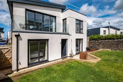 a white house with large windows and a yard at Beach Haven in Perranporth