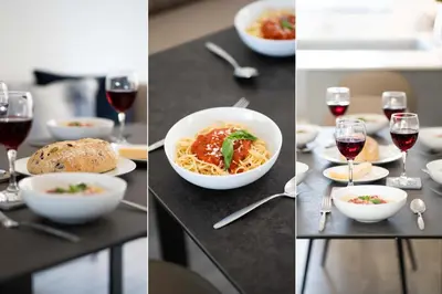 a table with a bowl of pasta and glasses of wine at Tides in Carbis Bay