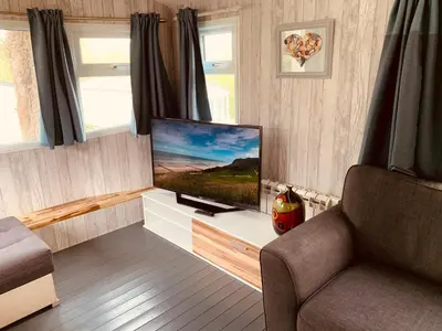 a living room with a flat screen tv and a chair at 94 Newquay Bay Resort pet friendly in Newquay