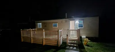 a small wooden cabin with a porch at night at 94 Newquay Bay Resort pet friendly in Newquay