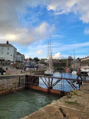 a dock with a sail boat on the water at Stunning Yacht Sea Lion in Charlestown Harbour, Cornwall in Charlestown