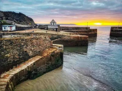 a sunset over the water next to a harbor at Stunning Yacht Sea Lion in Charlestown Harbour, Cornwall in Charlestown