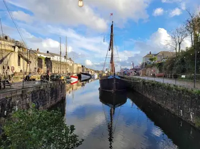 a boat is docked in a canal with buildings at Stunning Yacht Sea Lion in Charlestown Harbour, Cornwall in Charlestown