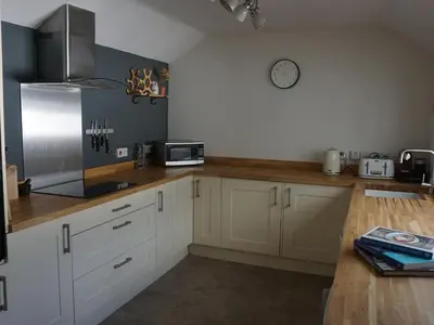 a kitchen with white cabinets and a clock on the wall at The Porthole in Port Isaac