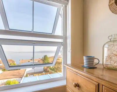 a room with a window with a view of the ocean at The Porthole in Port Isaac