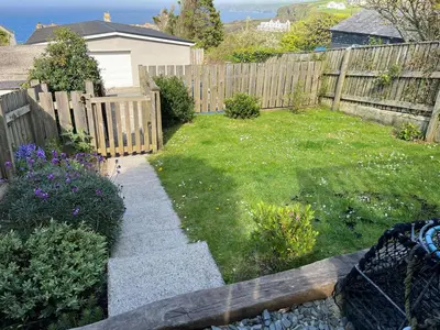 a backyard with a fence and a yard with flowers at The Porthole in Port Isaac