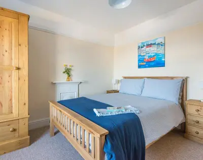 a bedroom with a bed with a blue blanket on it at The Porthole in Port Isaac